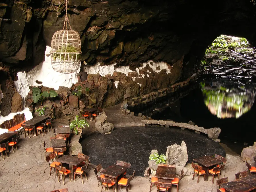 Restaurant tables in the cave of Jameos del Agua, with the lagoon opening behind